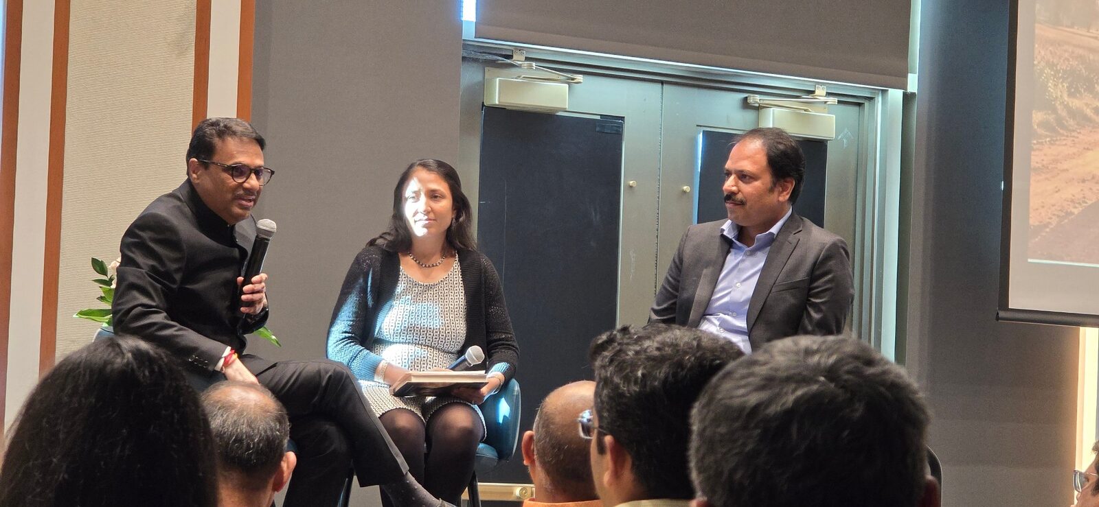 J. R. Sandadi speaking into a microphone during a panel conversation at the launch of The Eleventh Kilometer